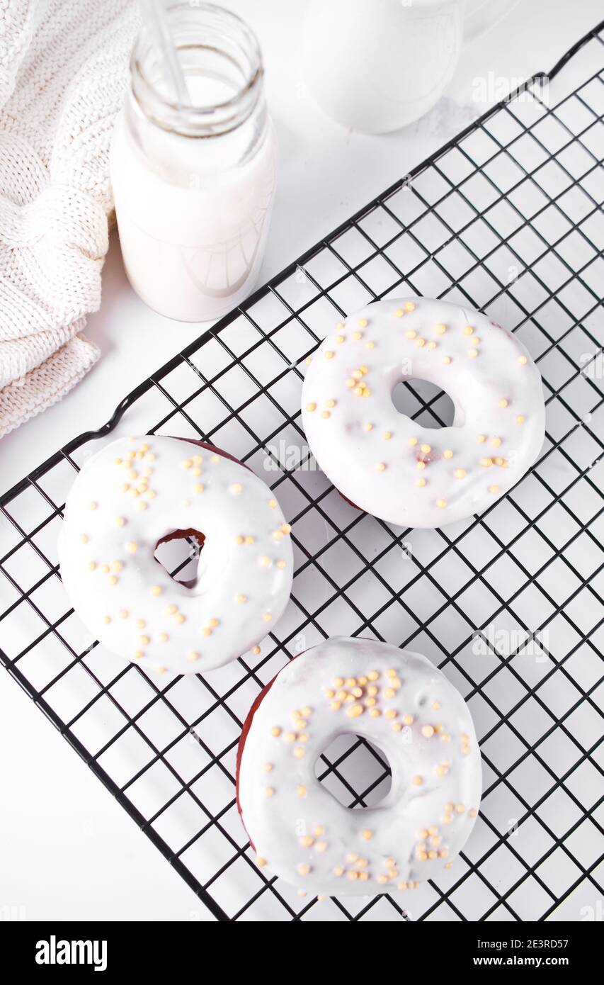 Donuts auf dem Backblech glasiert weiße Schokoladencreme oder Glasur und Flasche mit Milch auf dem Hintergrund Stockfoto