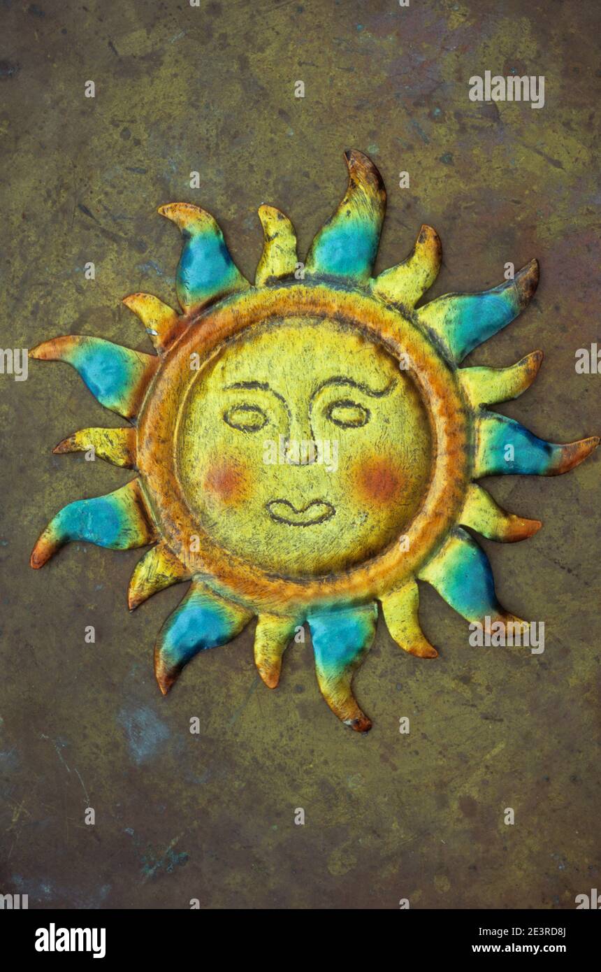 Gepresstes Zinnmodell der Sonne mit undurchschaubarem gelben Gesicht orange Wangen und blaue und gelbe Flammen Stockfoto
