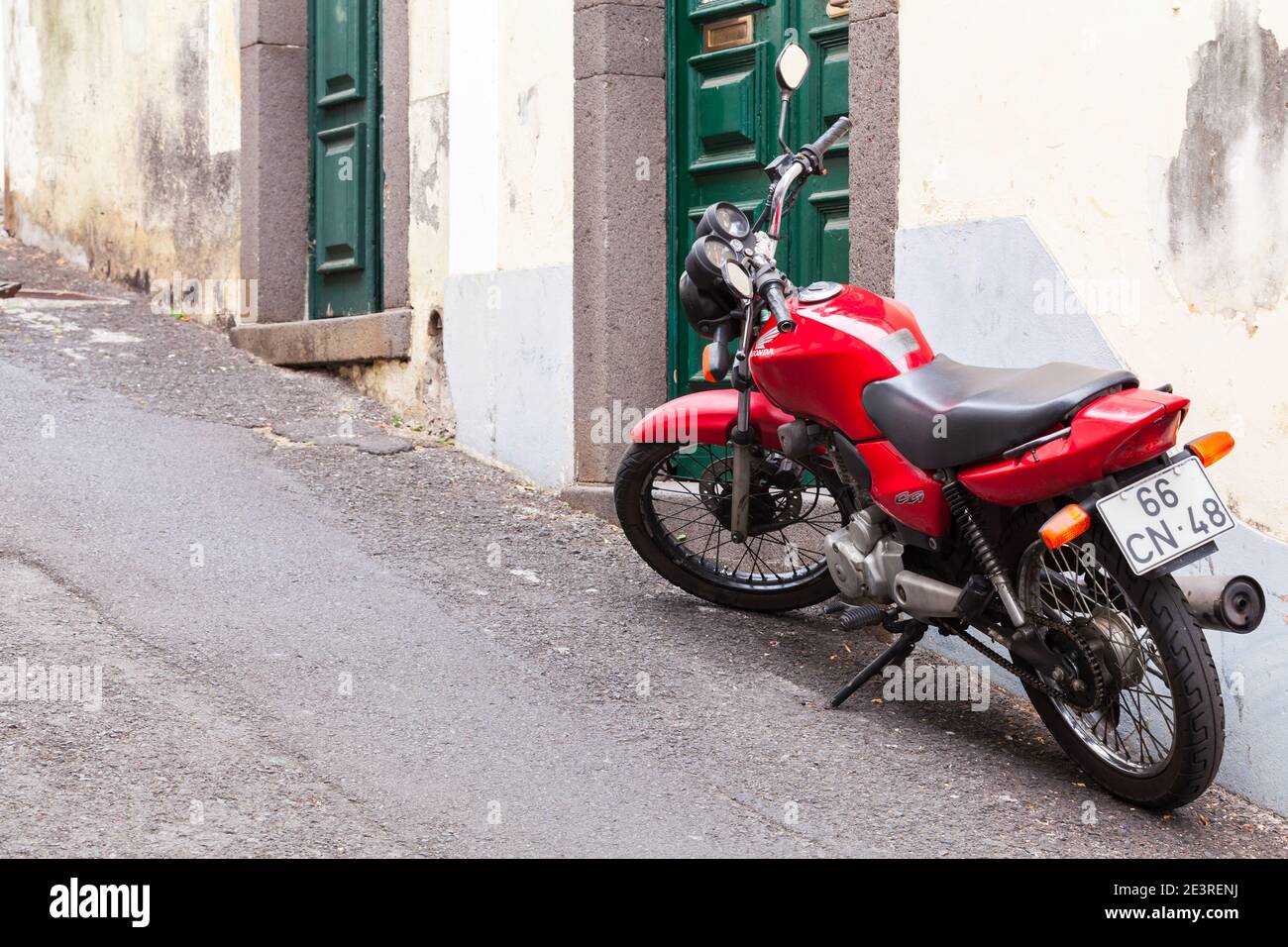 Funchal, Portugal - 24. August 2017: Rote Honda CG125 oder Honda CG steht in der Nähe der alten Mauer auf einer schmalen Straße, Rückansicht. Es ist ein Pendler motorcycl Stockfoto