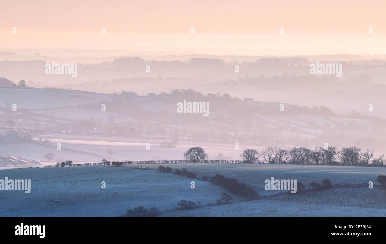 Das Licht der aufgehenden Sonne erzeugt wunderschöne, dunstige Schichten in der ländlichen Landschaft östlich von Almscliffe Crag in Lower Wharfedale. Stockfoto