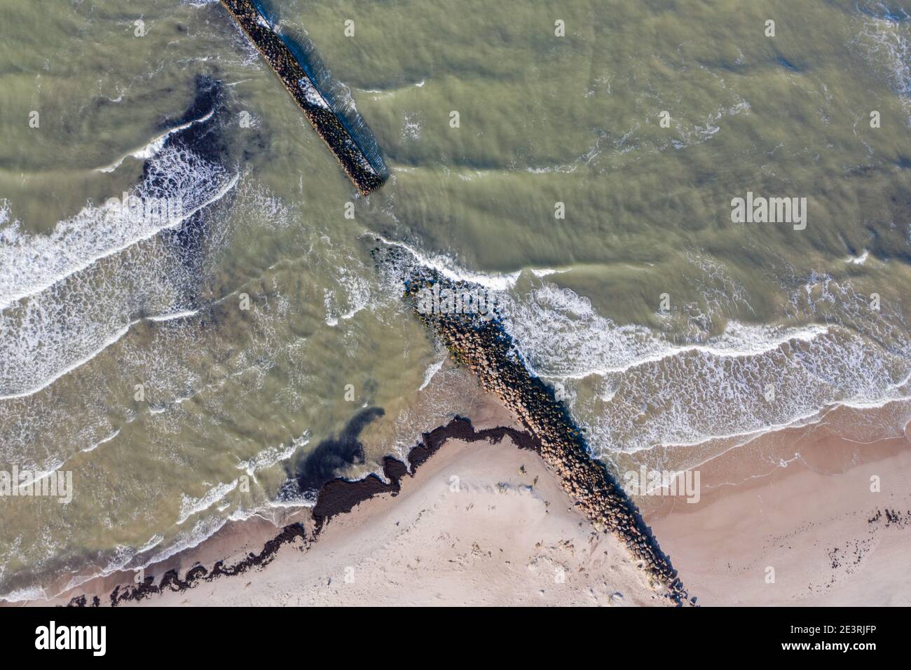 Luftaufnahme von oben nach unten von Wellen, die gegen alten Stein brechen Wellenbrecher Pier im Meer Stockfoto