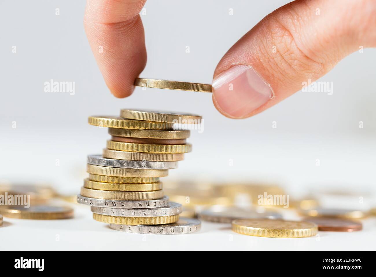 Finger, die einen Euro auf den Haufen von Münzen aus der Nähe Nach oben Stockfoto