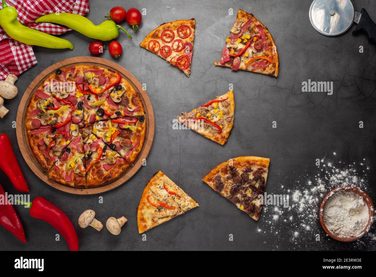 Pizzascheiben mit Thunfisch, Salami, Pilzen, Pepperoni und Gewürzen auf schwarzem Hintergrund, Kopierraum, Draufsicht Stockfoto