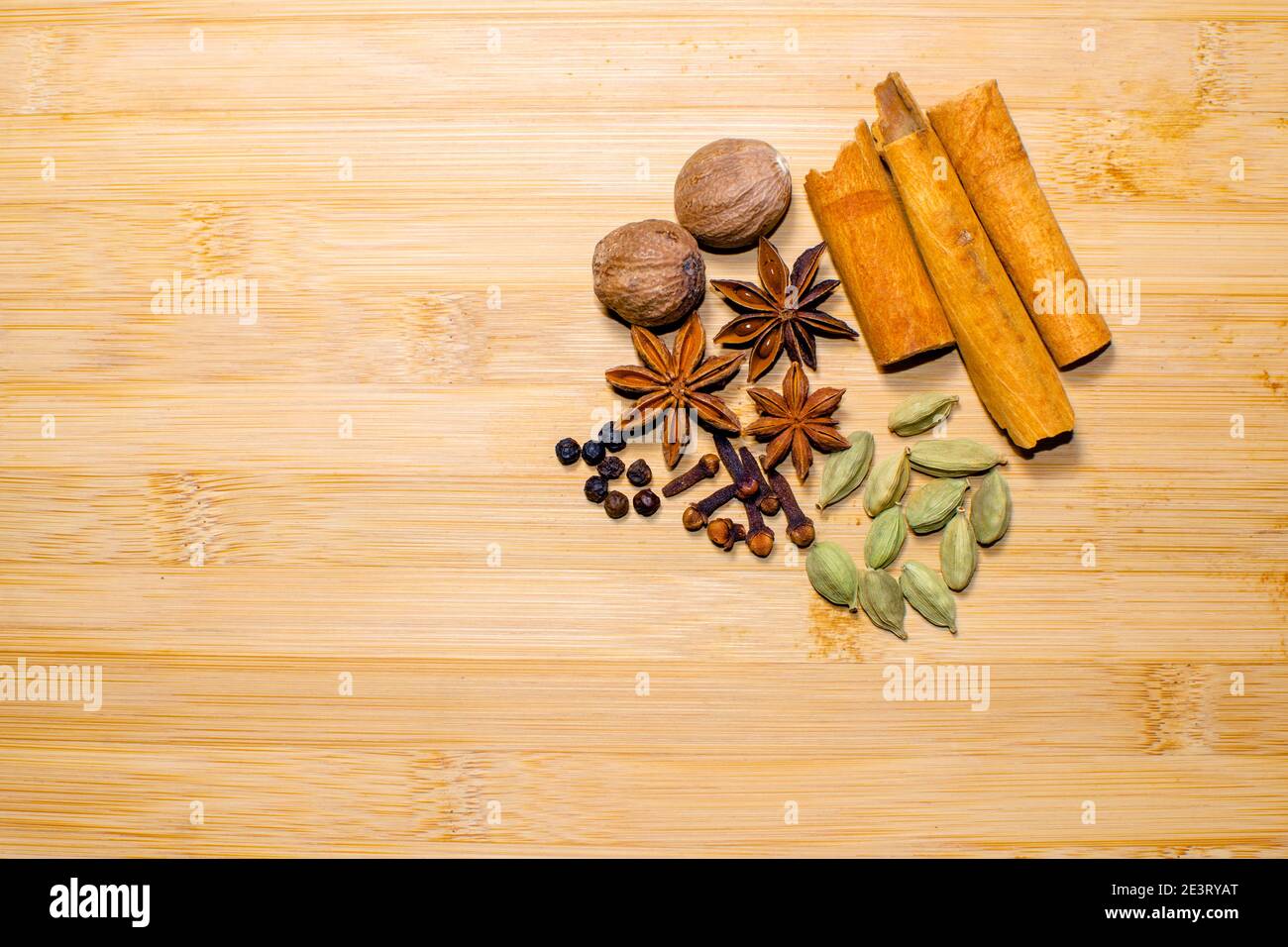 Verschiedene Gewürze Hintergrund, die Zimt, Kardamom, Nelke, schwarzer Pfeffer, Muskatnuss, Sternanis auf dem Holzhintergrund mit Kopierraum gehören. Stockfoto