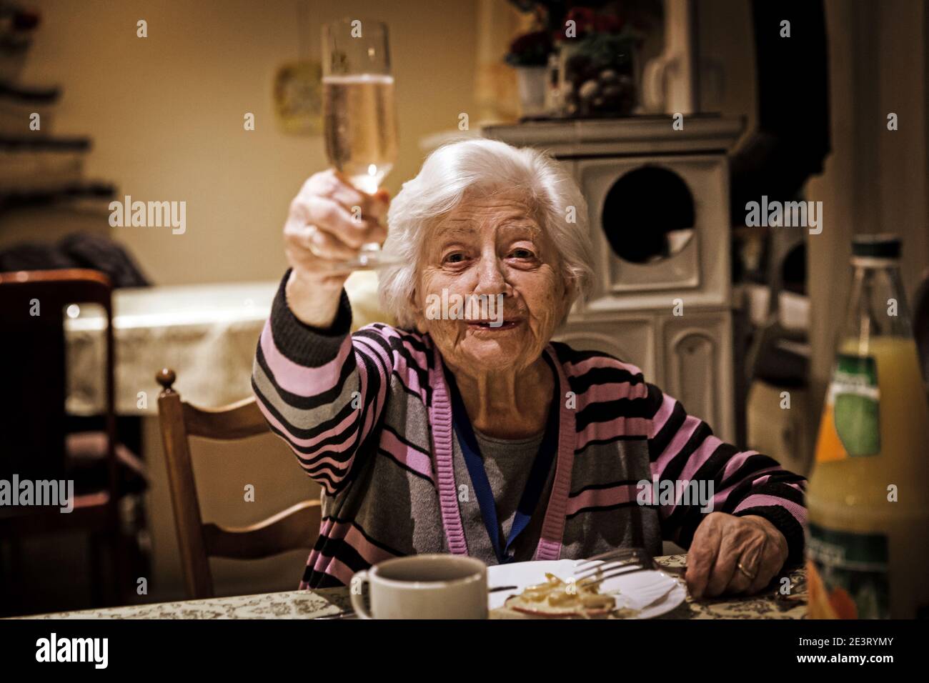 Ottilie Schütz 98, Toasten mit einem Glas Champagner im Speisesaal. Sie lebt im Seniorenheim auf dem Eifelhof in Marienrachdorf in Rheinland-Pfalz, wo die Senioren auch mit den Tieren in Kontakt kommen oder selbst am Hof arbeiten können. Stockfoto
