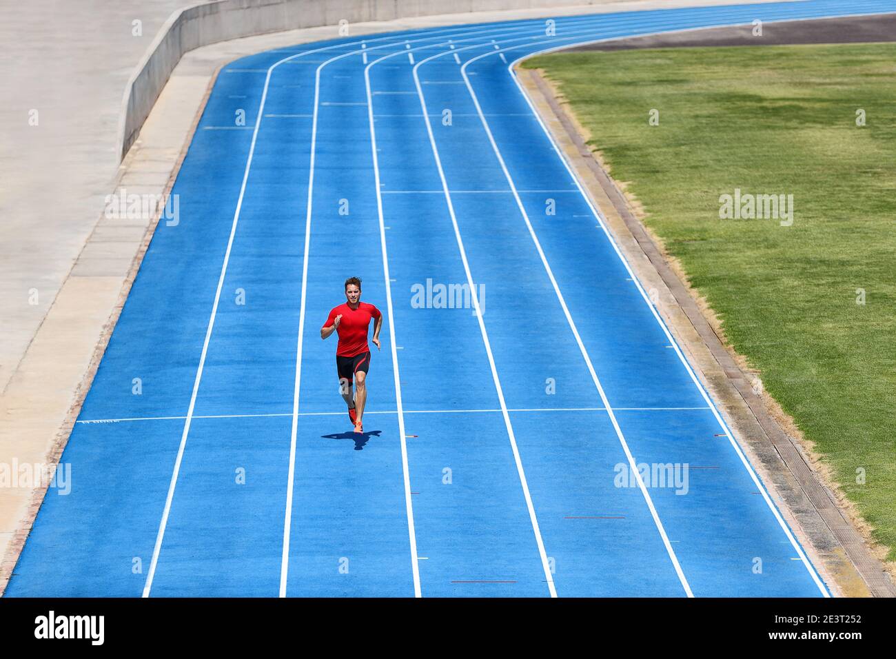 Sprinter Läufer Sportler Mann sprintet auf Outdoor-Strecke und Feldlaufbahnen im Stadion. Sport und Gesundheit Aktives Training auf blauen Bahnen. Stockfoto