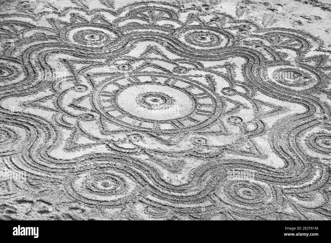Dekorative abstrakte geometrische Zeichnungen auf dem Sand. Urlaubskonzept am Strand. Schwarzweißfotografie Stockfoto