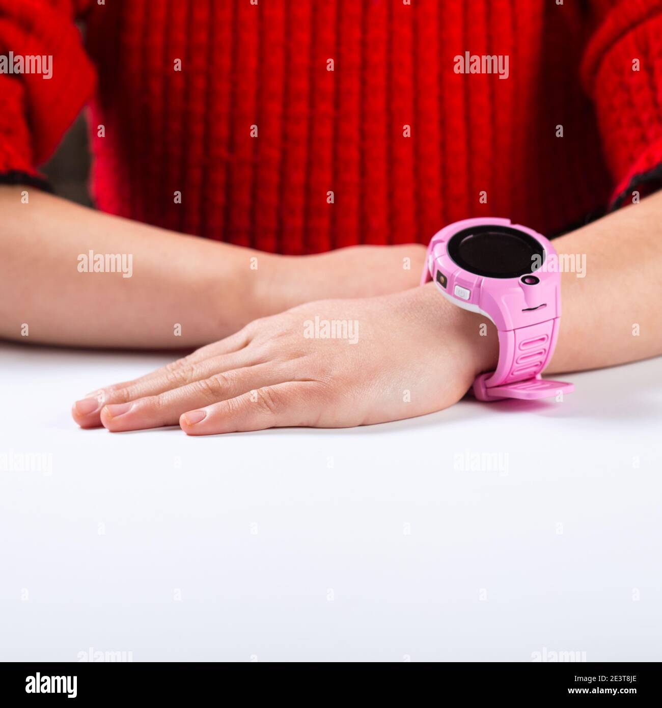 Kinderzeiger mit rosa Smart-Uhr auf einem weißen Tisch. Stockfoto