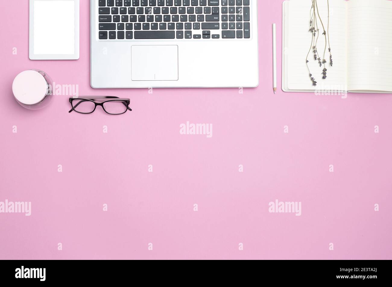 Eleganter, femininer Schreibtisch mit Laptop und modernen Büromerkmalen. Draufsicht. Speicherplatz kopieren. Flacher Raum. Rosa Hintergrund. Stockfoto