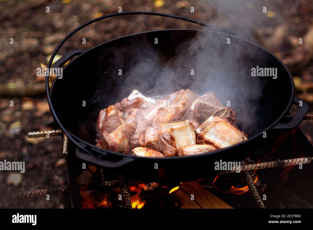 Kochen Pilaf in asiatischen Kessel auf dem Grill draußen im Wald. Ausgewählter Fokus. Tourismus consept Stockfoto