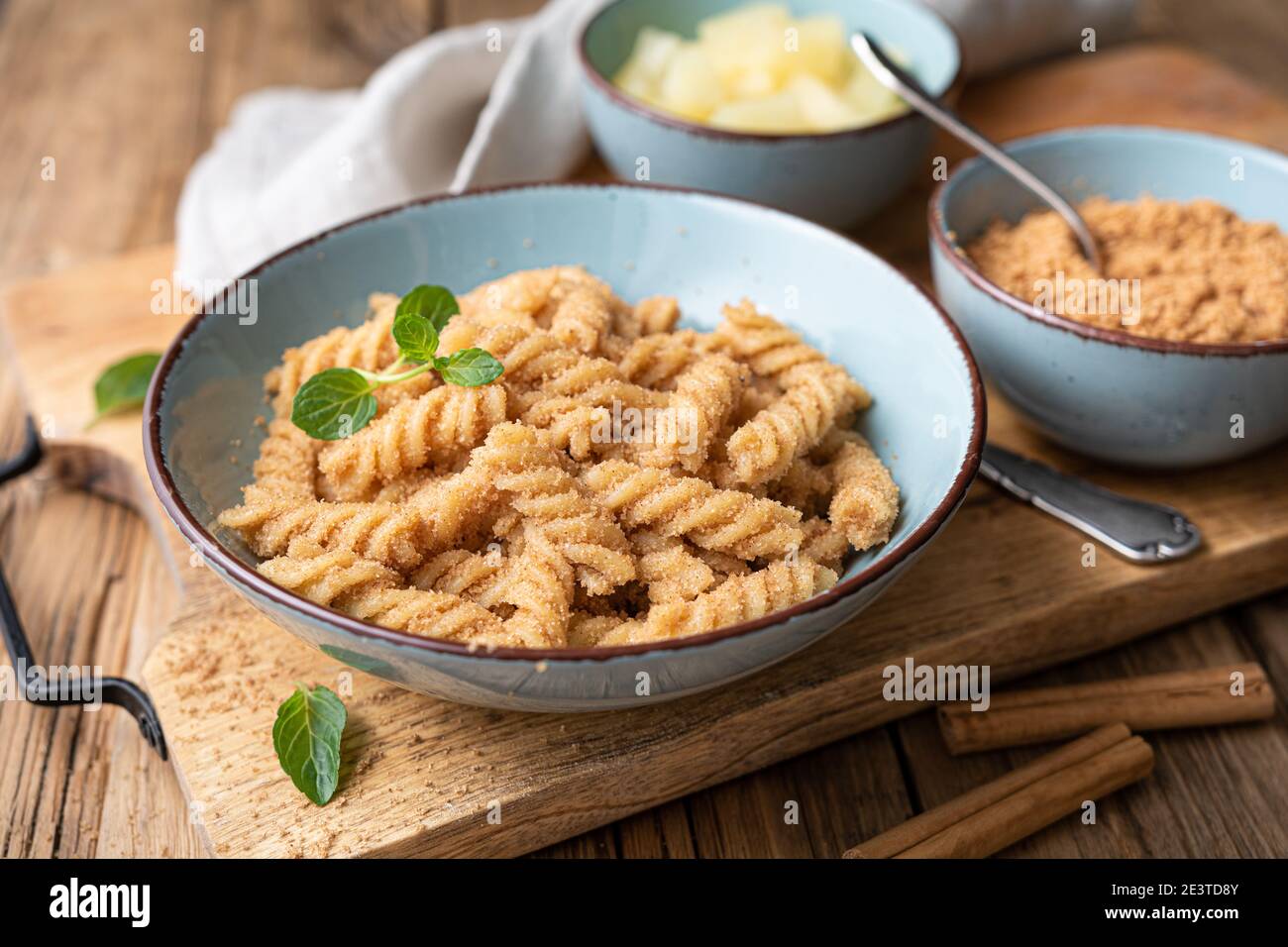Einfache Fusilli-Pasta mit süß gebratenem Grieß und Zimt, serviert mit Ananasstücken Stockfoto
