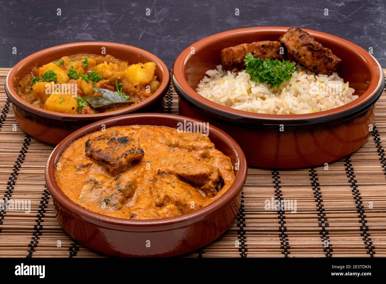Eine indische Mahlzeit mit Butter Huhn mit Bombay Kartoffel Aloo, Pilau Reis und Zwiebel bhajis Stockfoto