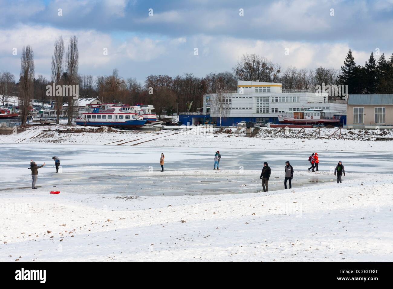 Brno, Tschechische Republik - 17. Januar 2021: Gefrorener Brünner Stausee, Menschen, die auf dem gefrorenen Stausee spazieren. Der Damm liegt am Fluss Svratka. Ort für Erholung, und ein Stockfoto