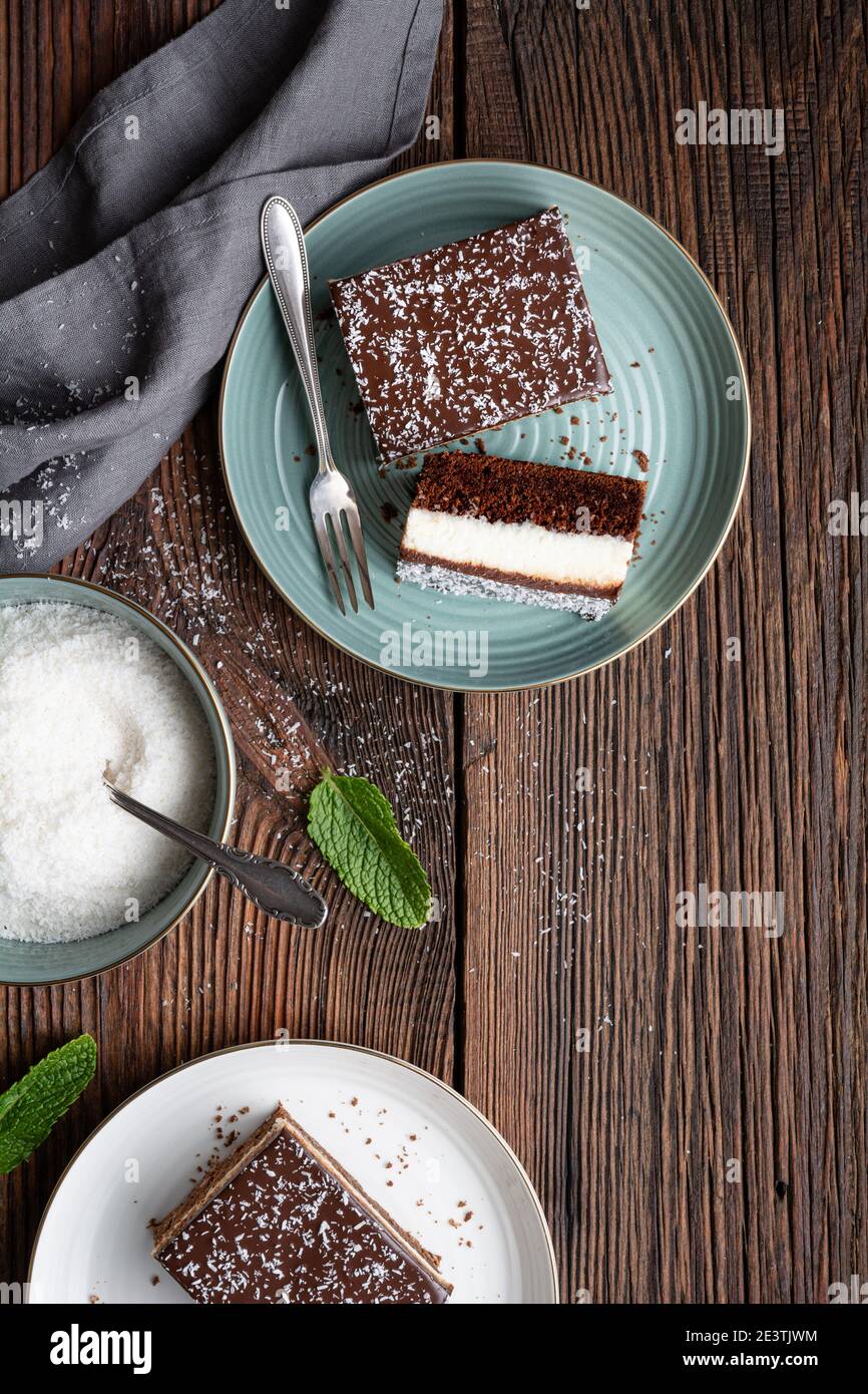Köstliche hausgemachte Dessert, fudgy Kokosnuss Brownies gekrönt mit Schokolade Ganache Glasur auf rustikalem Holzhintergrund Stockfoto
