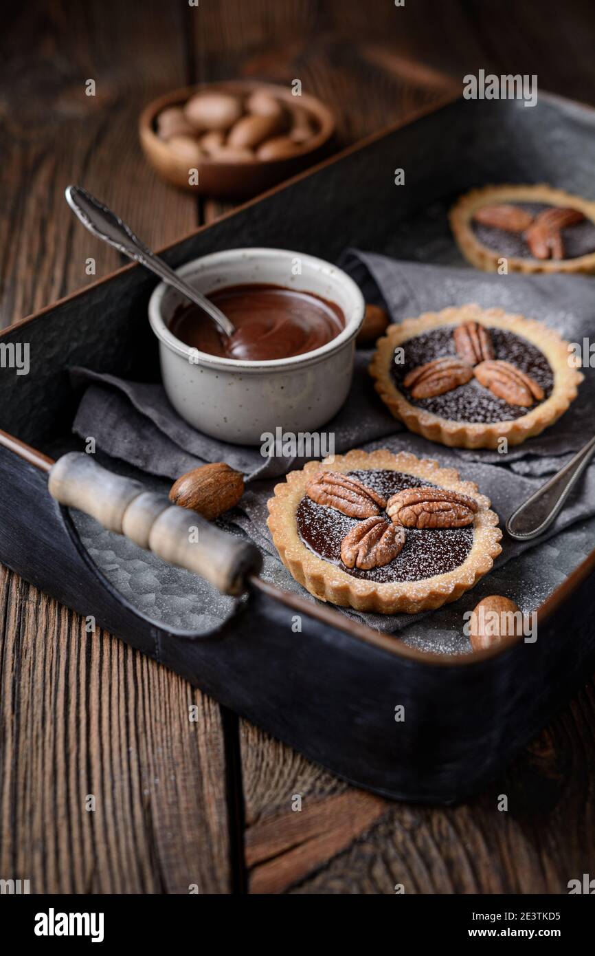 Dunkle Schokolade Ganache Torten mit Pekannüssen, mit Puderzucker auf rustikalem Holzhintergrund bestäubt Stockfoto