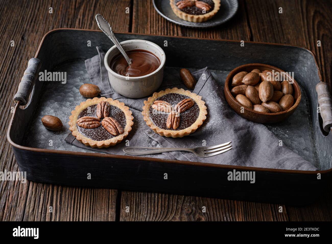 Dunkle Schokolade Ganache Torten mit Pekannüssen, mit Puderzucker auf rustikalem Holzhintergrund bestäubt Stockfoto