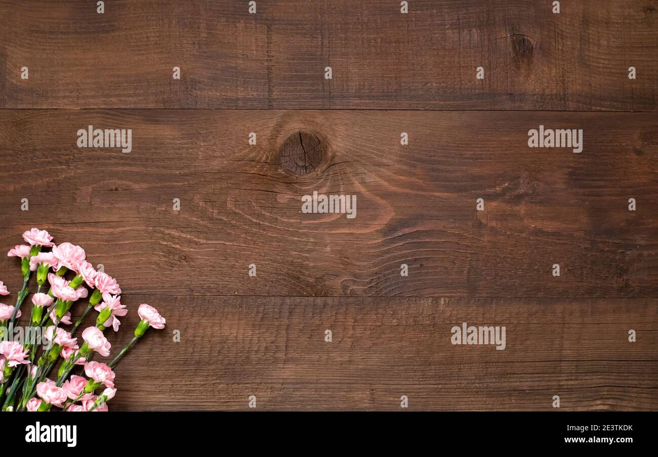 Rosa Blumen auf dunkelbraunem Holztisch mit Kopierraum. Stockfoto