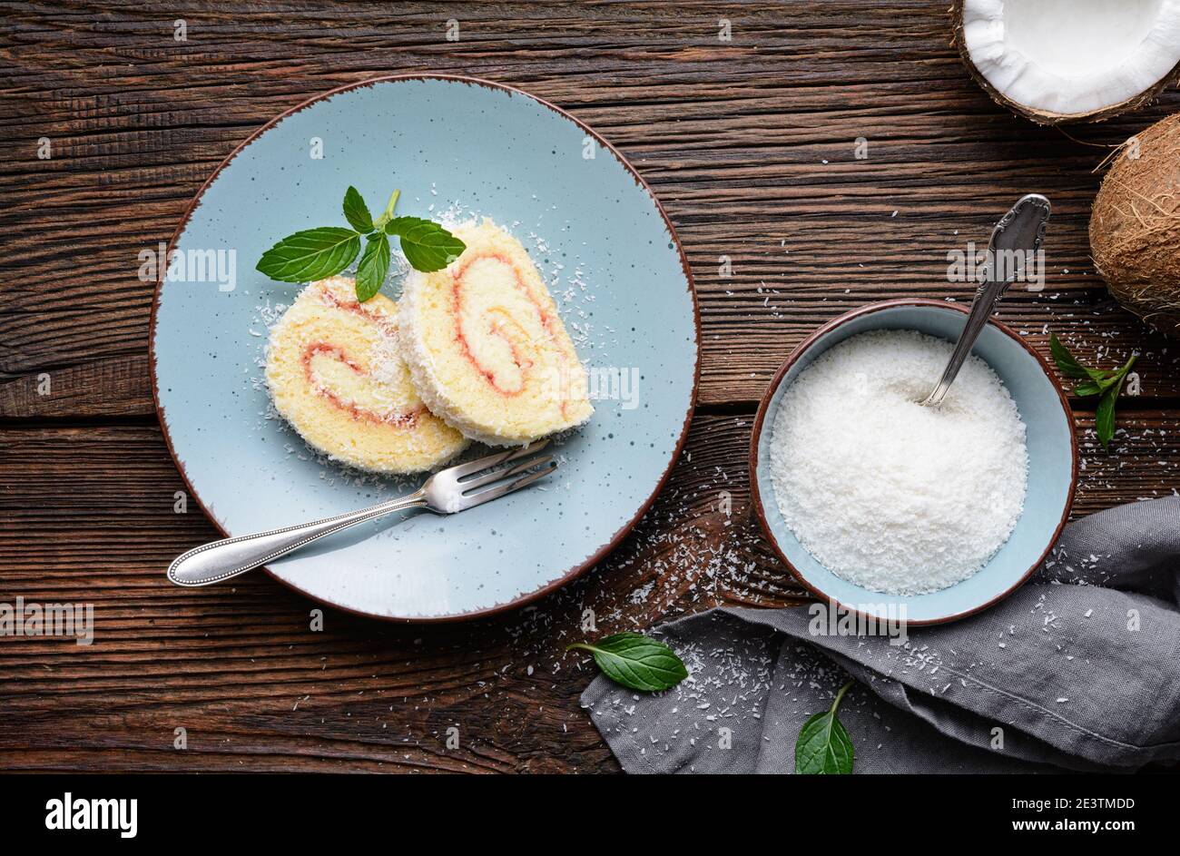 Köstliches Dessert, Kokosnussroulade Scheiben gefüllt mit Vanille und Rum Buttercreme auf rustikalem Holzhintergrund Stockfoto