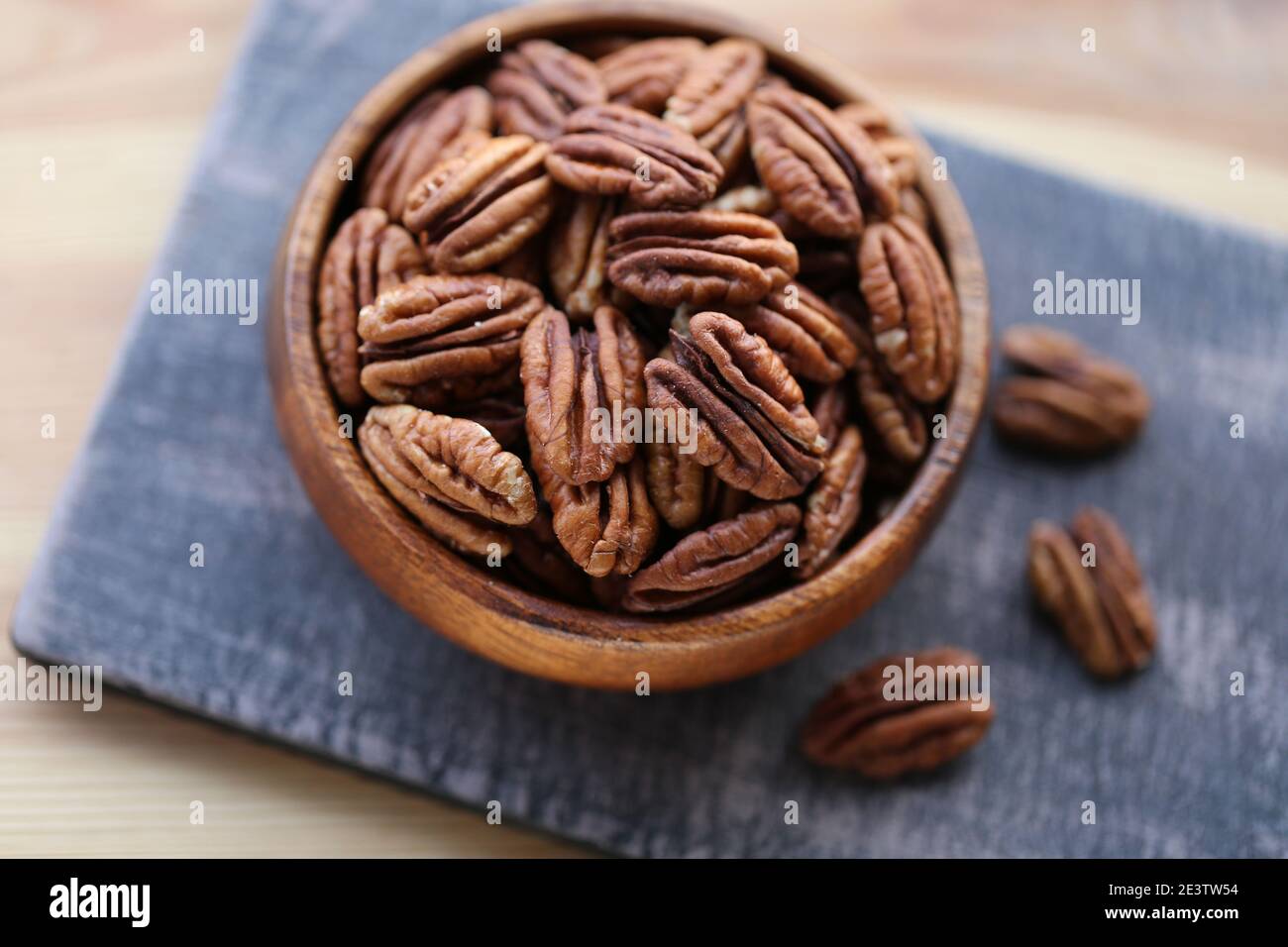 Pekannuss Nahaufnahme in einem runden Holzbecher auf einem schwarzen Shabby Board auf Holztisch Hintergrund.Nüsse und Samen. .gesunde Fette.Heap geschälte Pekannuss Stockfoto