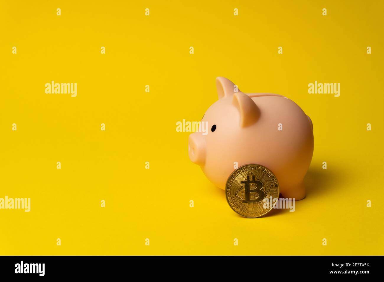 Rosa Schwein als Geldbox auf gelbem Hintergrund mit BTC Münze Stockfoto