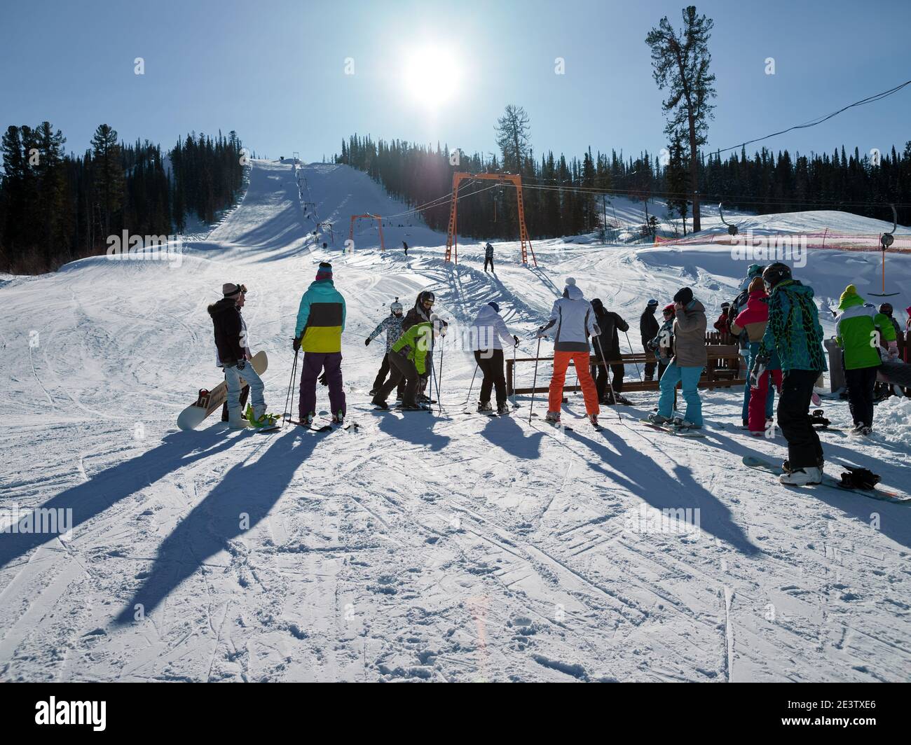 Skifahrer stehen an einem sonnigen Wintertag für den Skilift vor einer Abfahrtspiste in einem Skigebiet an. Stockfoto