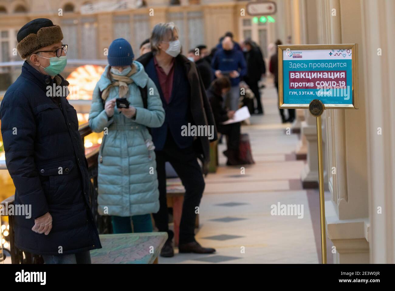 Moskau, Russland. 20th. Januar 2021 Bürger mit Gesichtsmasken stehen in der Schlange vor einer mobilen Impfeinheit COVID-19 im KAUGUMMI-Kaufhaus im Zentrum von Moskau, Russland. Seit Januar 18 hat Russland mit dem Sputnik V-Impfstoff mit einer Massenimpfung gegen die neuartige Coronavirus-Infektion COVID-19 begonnen. Auf dem Banner steht: "Die Impfung COVID-19 wird hier durchgeführt" Stockfoto