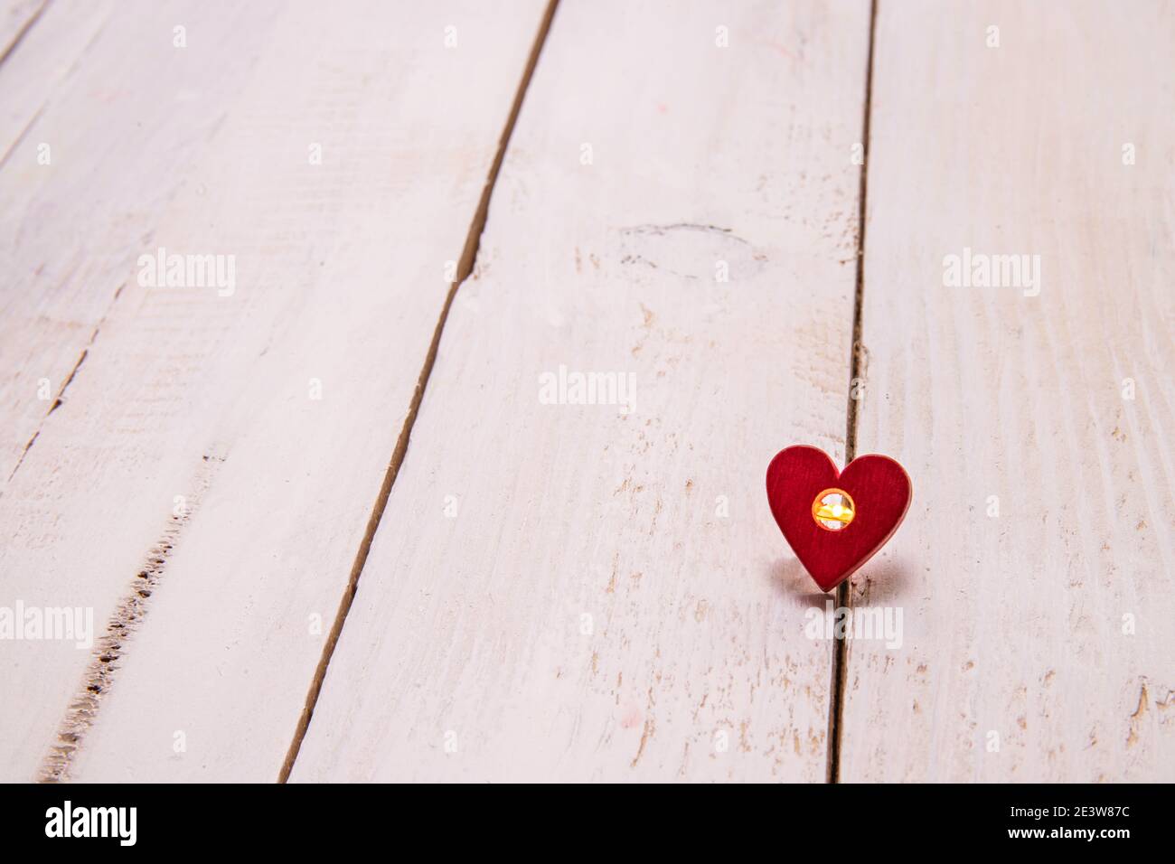 Ein kleines Licht in einem Herzen auf einem weißen Holzhintergrund. Liebe mit einem einfachen und tiefen Gedanken auszudrücken. Stockfoto