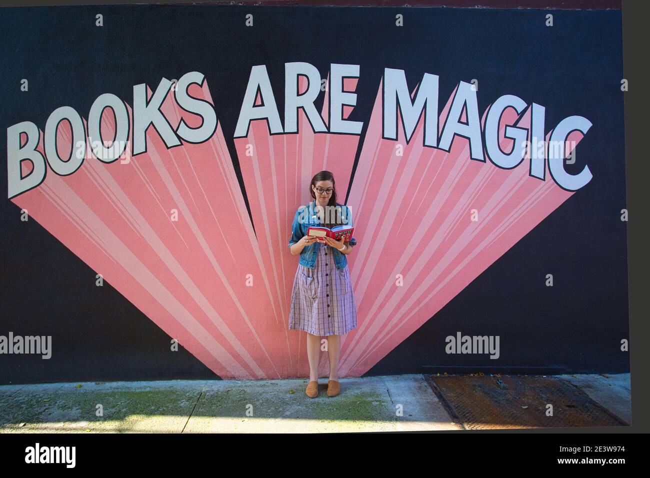 USA / New York City / Brooklyn / Buchhandlungen / Attraktive Frau hält Buch außerhalb des Geschäfts Indie Buchhandlung Books are Magic in Brooklyn , New York . Stockfoto