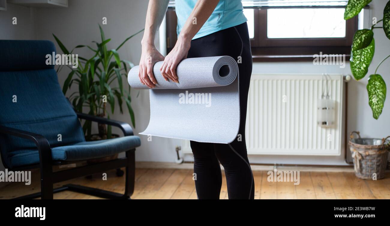 Frau faltende Yogamatte zu Hause Stockfoto