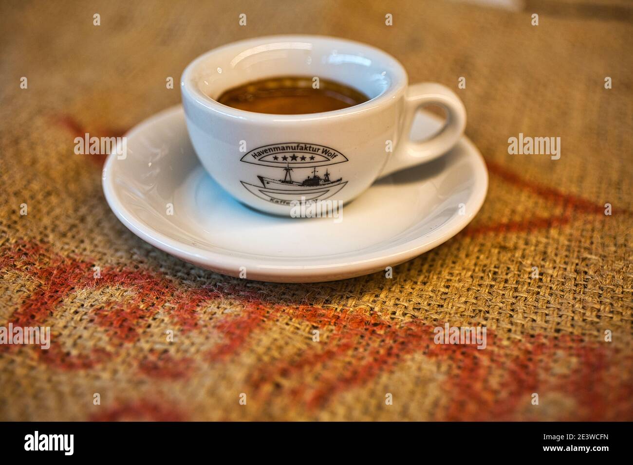 Nahaufnahme von Espresso, der in einer Tasse auf einem Kaffeebohnensack geschossen wurde Stockfoto