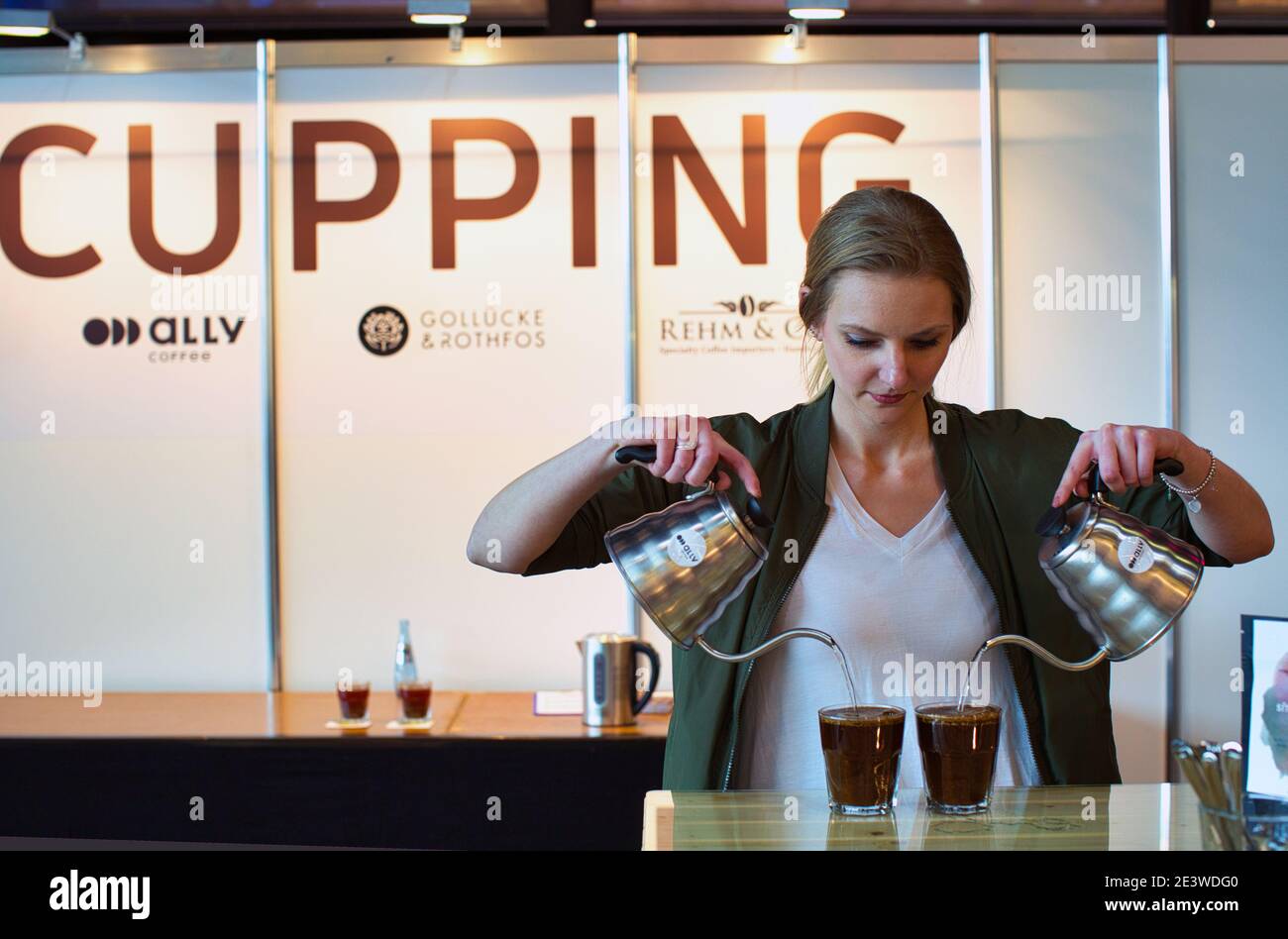 Weibliche Barista gießt Wasser in eine Tasse gemahlenen Kaffee Stockfoto