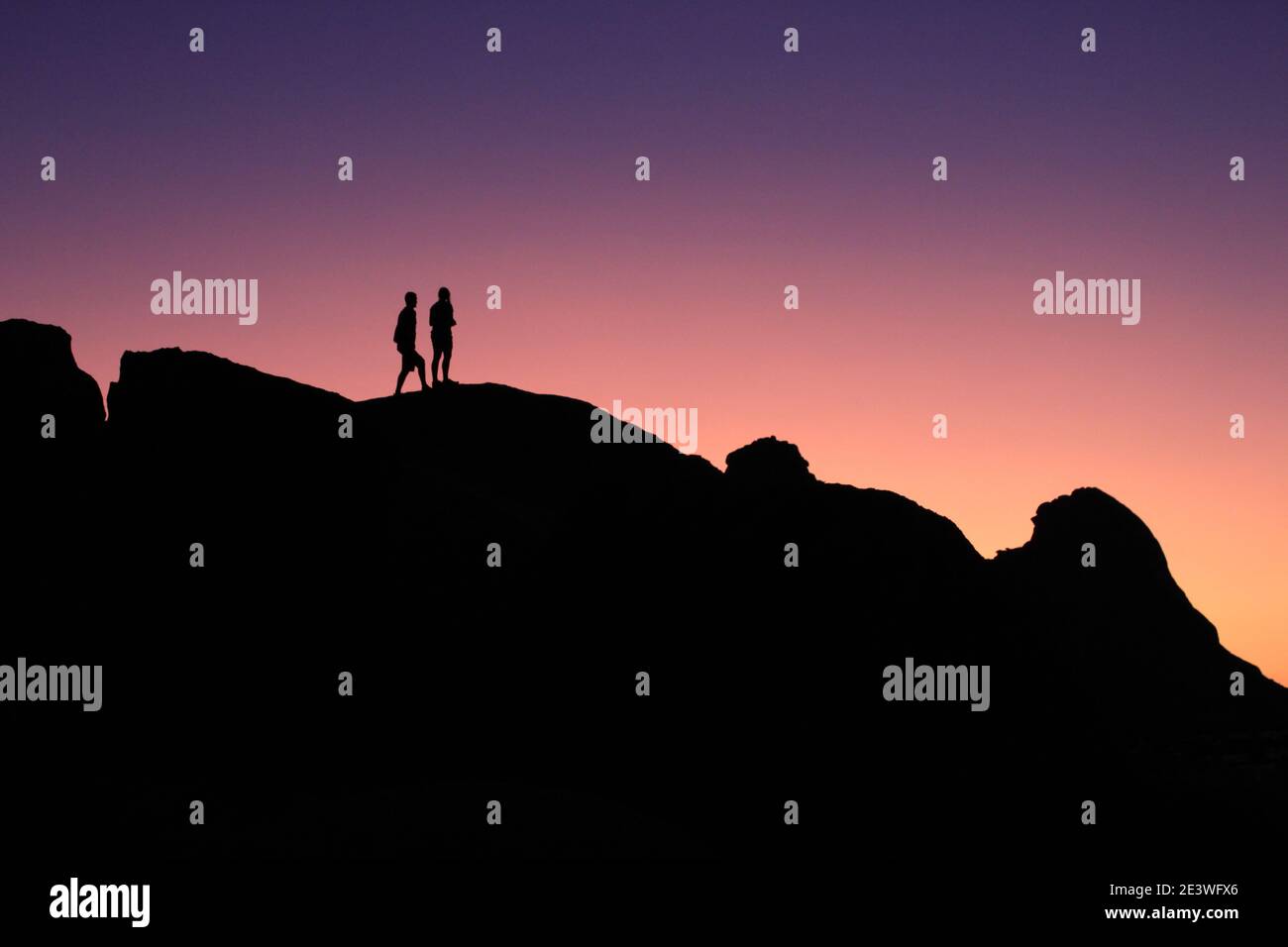 Menschen Silhouetten vor einem lila Sonnenuntergang Stockfoto