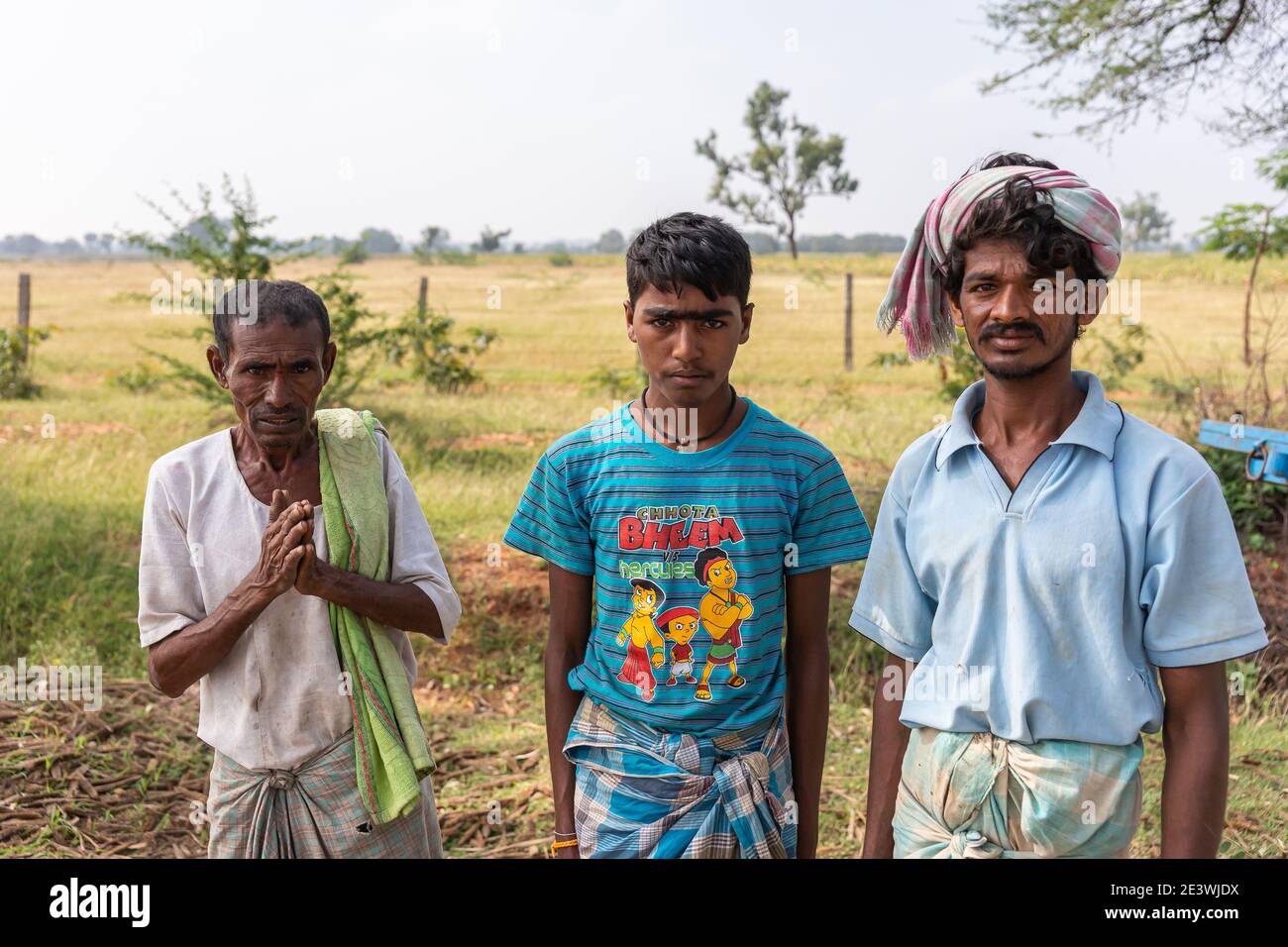 Halagere, Karnataka, Indien - 6. November 2013: Brust und Kopf Nahaufnahme von 3 Farmhände, in blauen Hemden, Arbeiten auf Hirsefeld. Verblasste Landschaft wie Bac Stockfoto