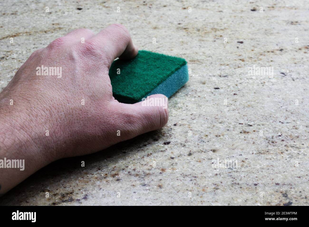 Ein Mann reinigt eine Arbeitsplatte aus Granit mit einem Schwamm Stockfoto