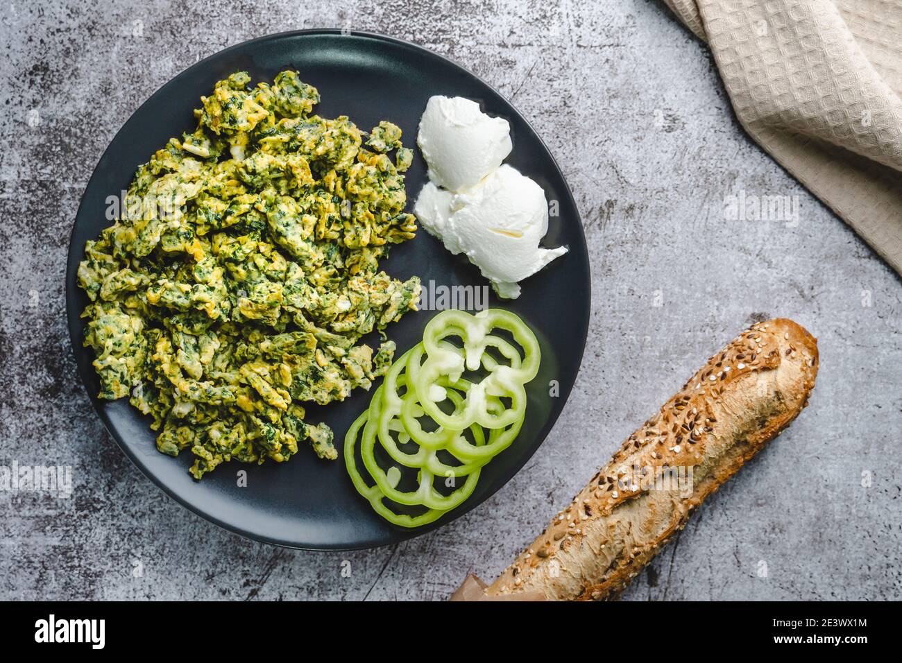 Bio-Rührei mit Spinat in Teller auf Marmortisch Und Brot Stockfoto