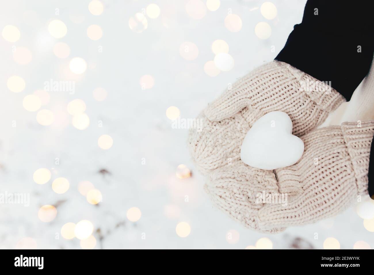 Schnee Herz Schneeball in Mädchen Handschuhen. Unscharfer Hintergrund Stockfoto