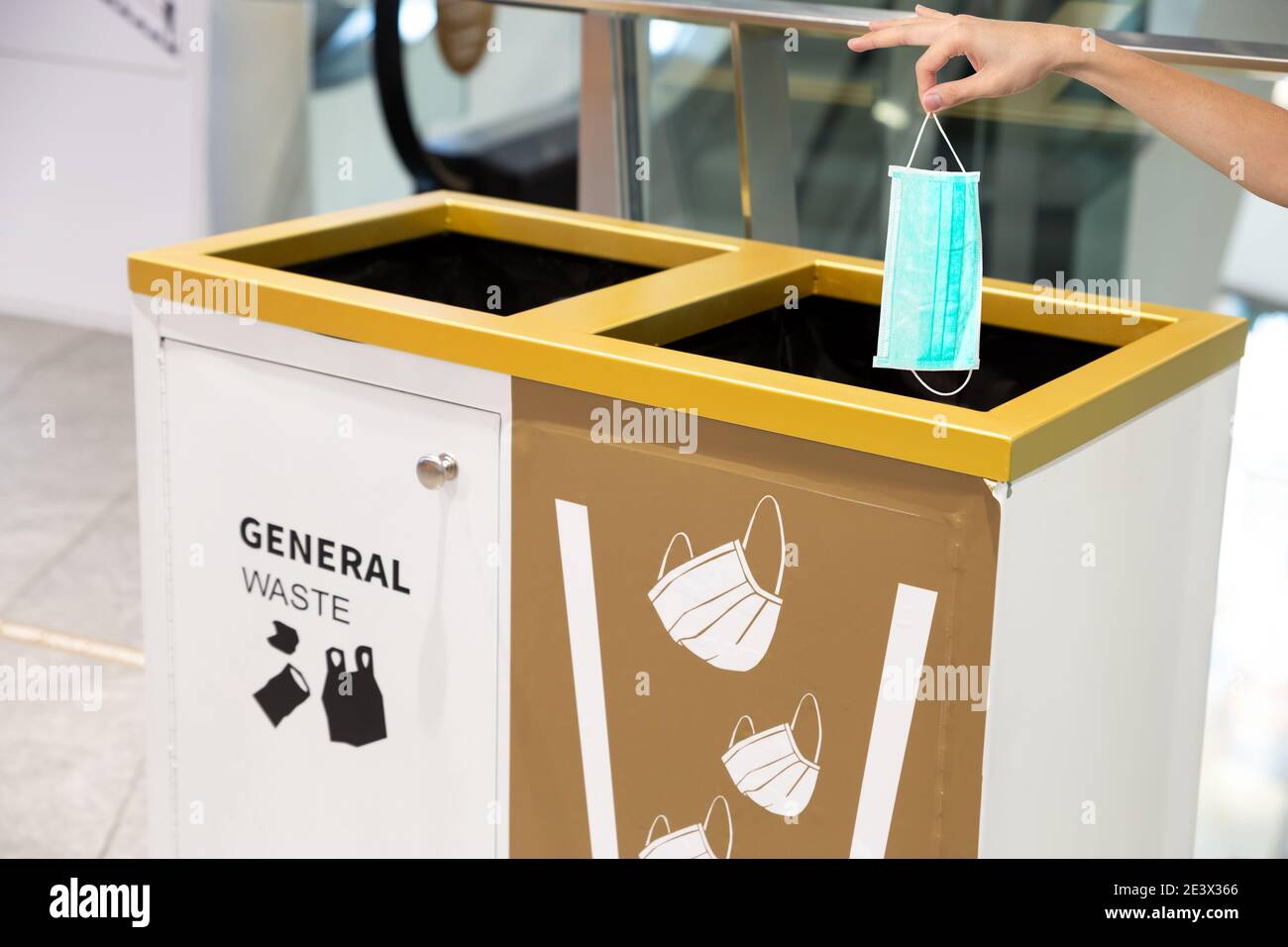 Menschen Hand werfen medizinische Gesichtsmaske in einen Papierkorb in einem Einkaufszentrum. Der richtige Weg, um Coronavirus oder Covid-19 Konzept zu schützen. Stockfoto