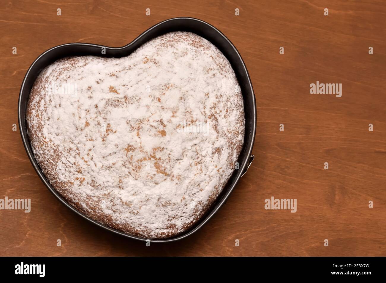 Herzförmiger Kuchen mit Puderzucker bestäubt, frisch gebacken mit Liebe zum Geburtstag und Urlaub Stockfoto