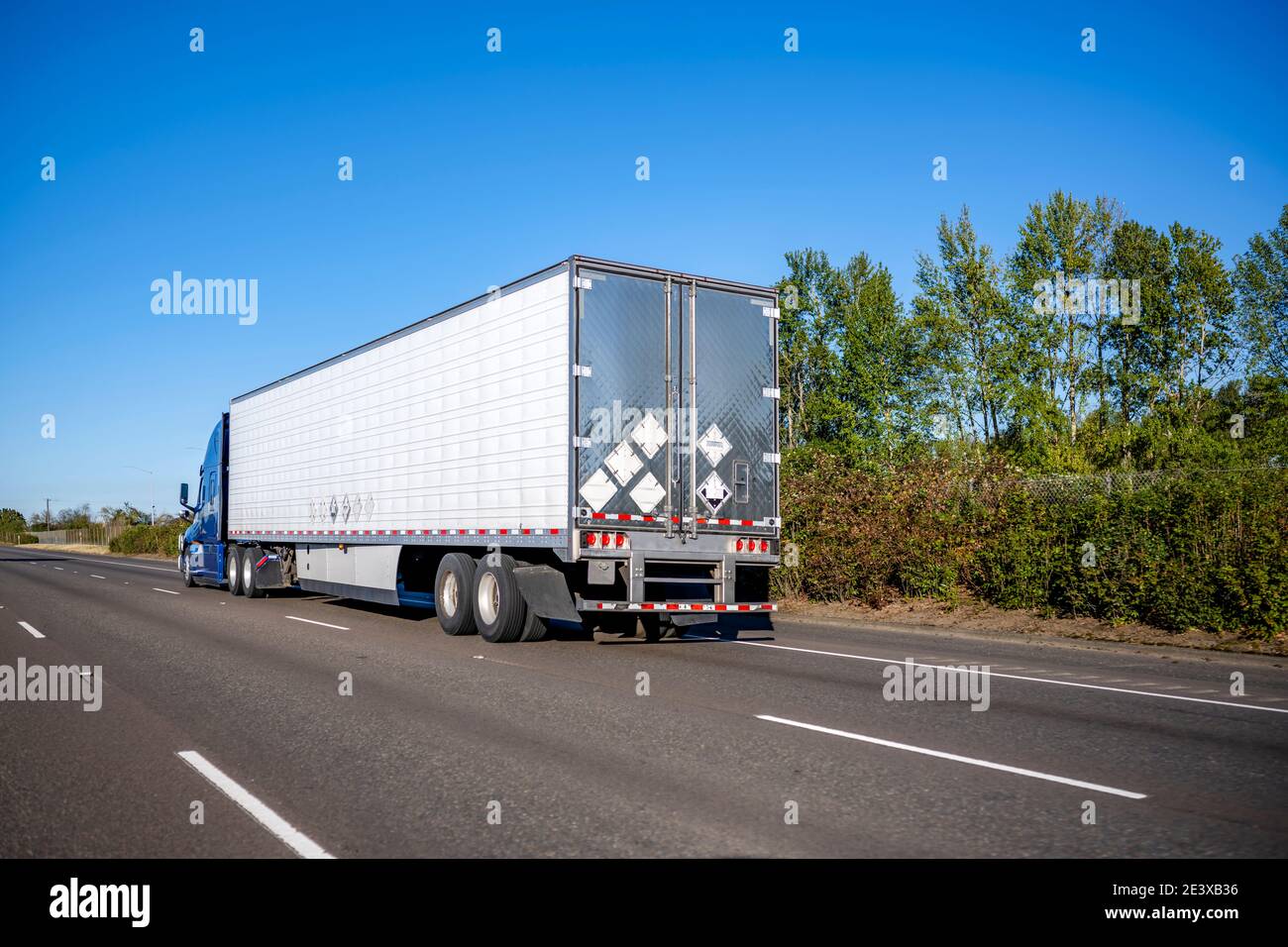Blaue Industrie Langstrecke große Rig semi-Truck mit hoch Kabine, die gefrorene Ladung im Kühlraum transportiert, der auf dem Fahrzeug fährt Die breite Mehrzeilenteile Stockfoto