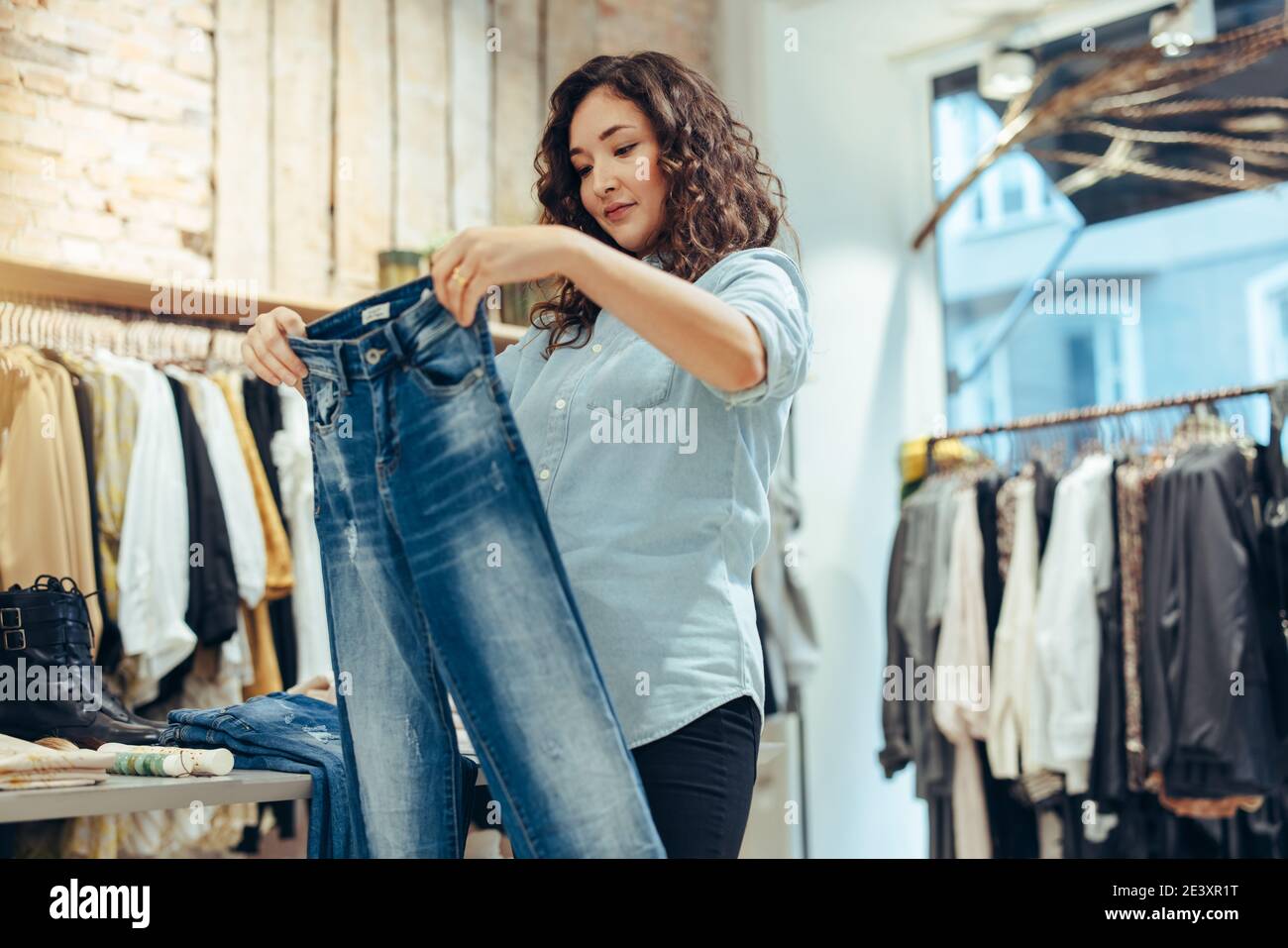Frau, die in einem Modehaus Jeans anschaut. Weibliche Kundin, die Jeans im Bekleidungsgeschäft kauft. Stockfoto