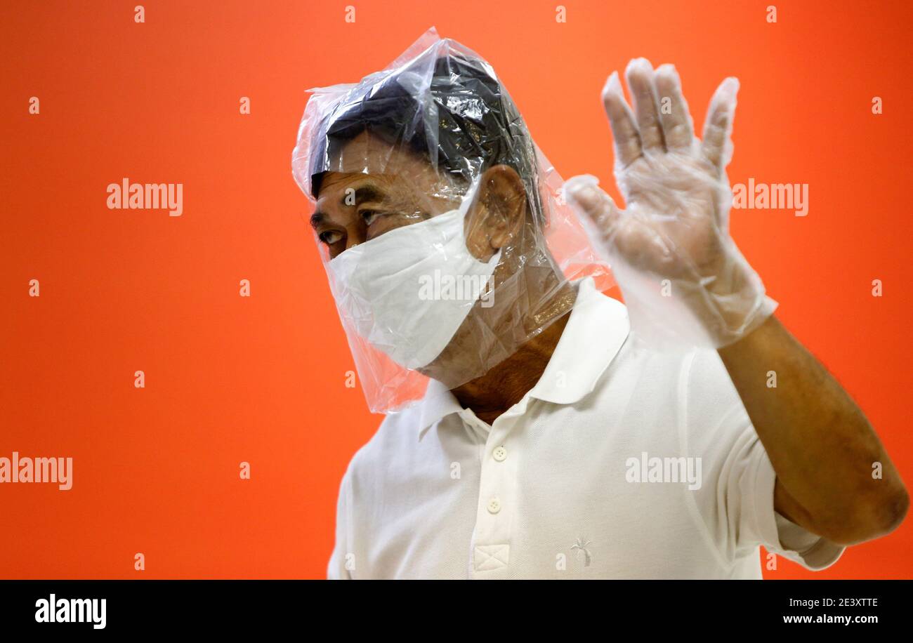 Ein Mann, der als vorbeugende Maßnahme gegen die Verbreitung von Covid19 eine Gesichtsmask und Plastiktüte über dem Kopf trägt, hört als Führer der Progressiven Bewegung, Thanathorn Juangroongruangkit, während einer Pressekonferenz in der Zentrale der Progressiven Bewegung in Bangkok. Thanathorn Juangroongruangkit hat am Mittwoch auf seiner Facebook-Seite gepostet, dass die Reaktion der thailändischen Regierung auf seine Erklärung vom Montag über die Transparenz des Covid-19-Impfstoffes seinen Zweifel nur verstärkt, dass ein im Besitz der Royally befindliches Pharmaunternehmen in den Impfplänen des Landes eine Sonderbehandlung erhalten hatte. Stockfoto