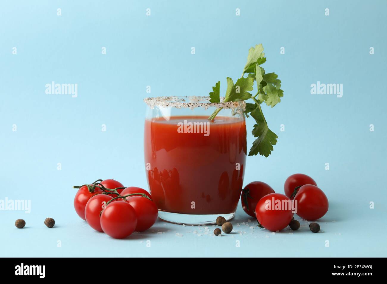 Glas Bloody Mary mit Kirschtomaten und Petersilie auf Hellblau, ein erfrischender Bloody Mary-Cocktail mit gesalzenem Rand Stockfoto