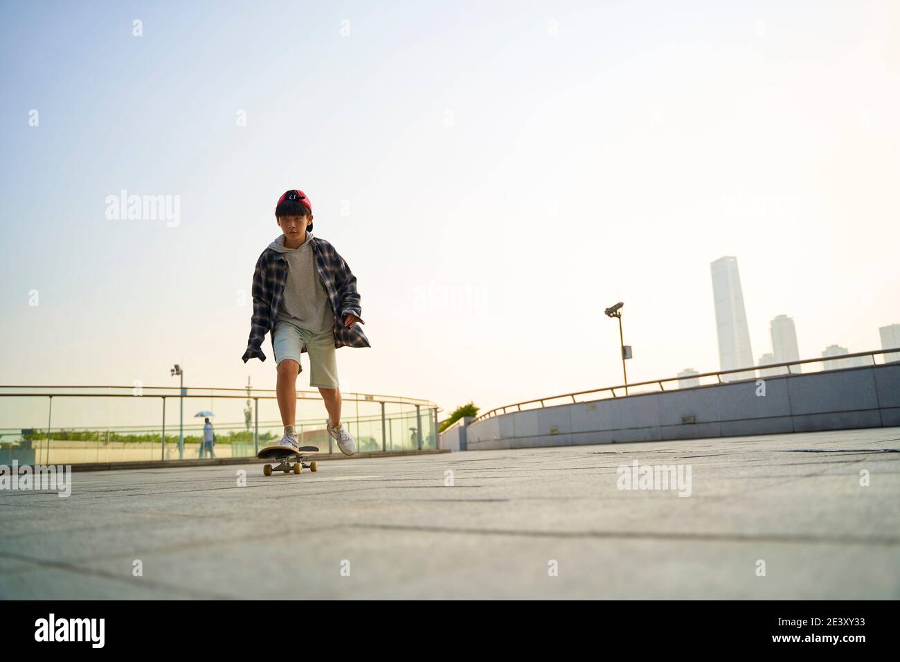 Teenager asiatische Kind Skateboarding im Freien auf einer Fußgängerbrücke Stockfoto