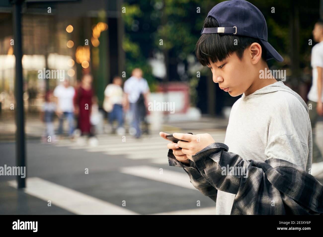 Teenager asiatische Kind Blick auf Handy, während auf der Straße zu Fuß Stockfoto