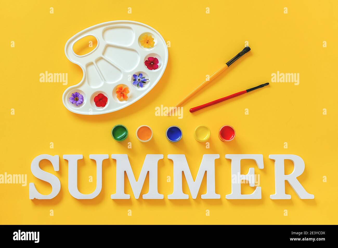 Text Sommer, bunte Blumen auf künstlerischer Palette, Pinsel und Gouache auf gelbem Hintergrund. Kreatives Konzept Sommer Farben malen. Draufsicht flach Stockfoto