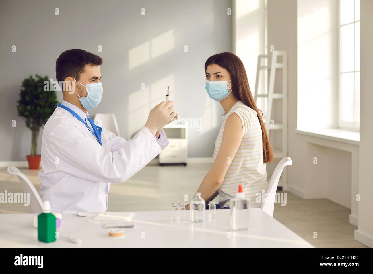 Mann Arzt in Uniform und medizinische Maske Vorbereitung Spritze vor Impfungen Stockfoto