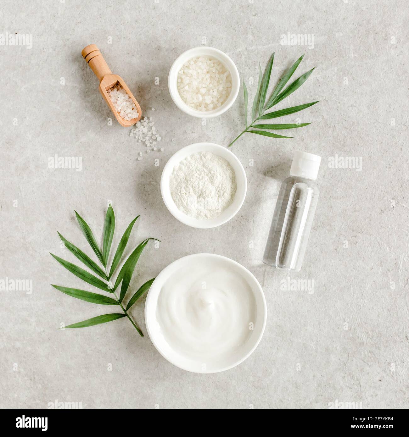 Weibliche Haut- und Körperpflege Kosmetik-Produkte Set: Gesichtscreme, kosmetische Ton, Meersalz, Flasche mit Hyaluron auf grauem Marmorboden. Stockfoto