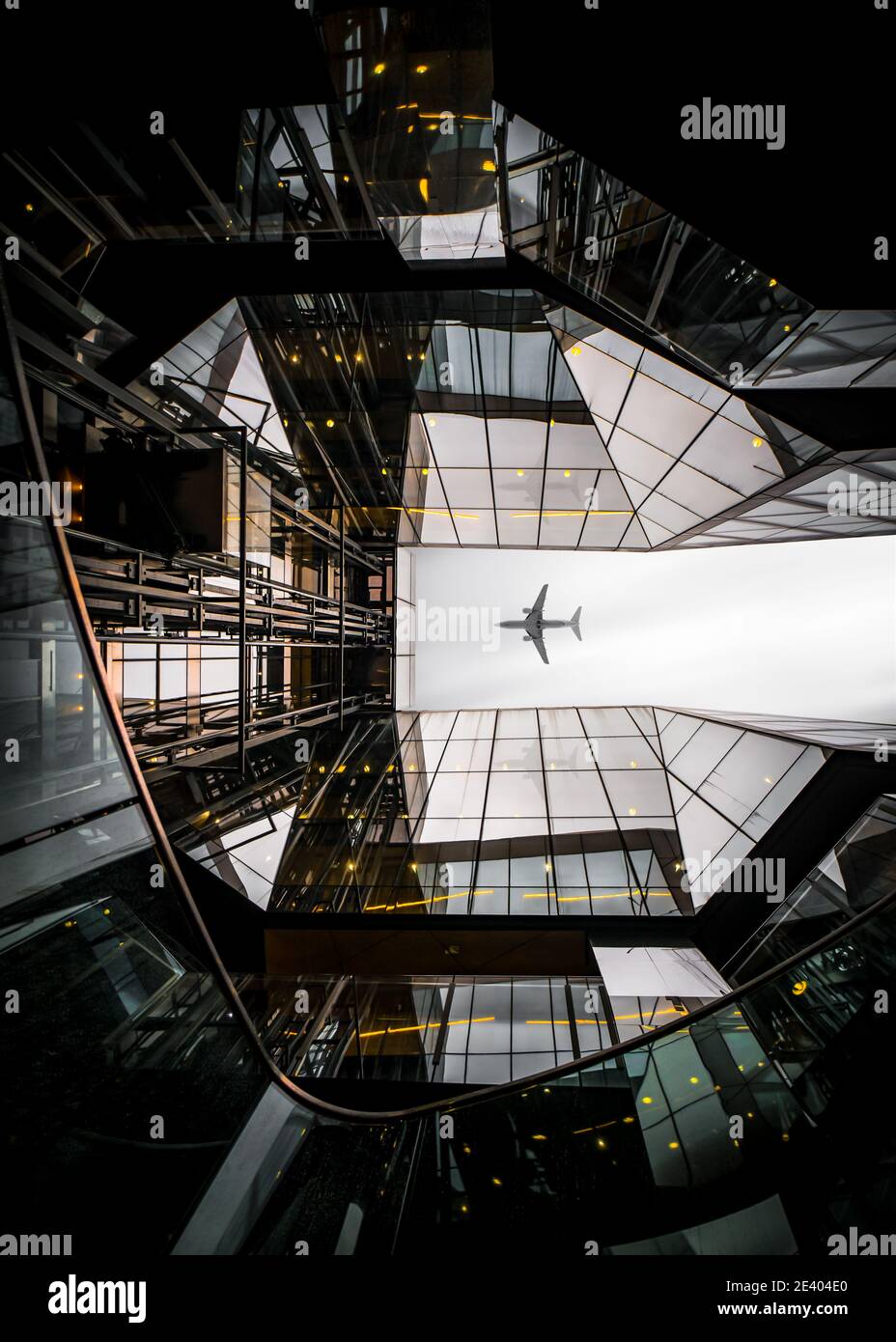 Jumbo Jet Fracht Passagierflugzeug fliegen über moderne Architektur Glas Reflection Sky Scraper Gebäude im Stadtzentrum dramatische Aussichtspunkt symmetrisch Stockfoto