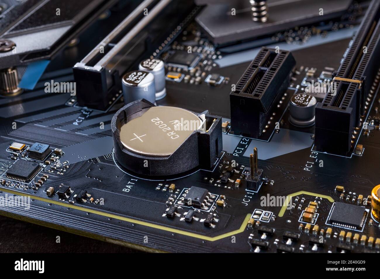 CMOS-Backup-Batterie zur Stromversorgung von BIOS-Einstellungen und Echtzeituhr auf einem modernen schwarzen Motherboard. Komponenten der Hauptplatine des Computers. Stockfoto