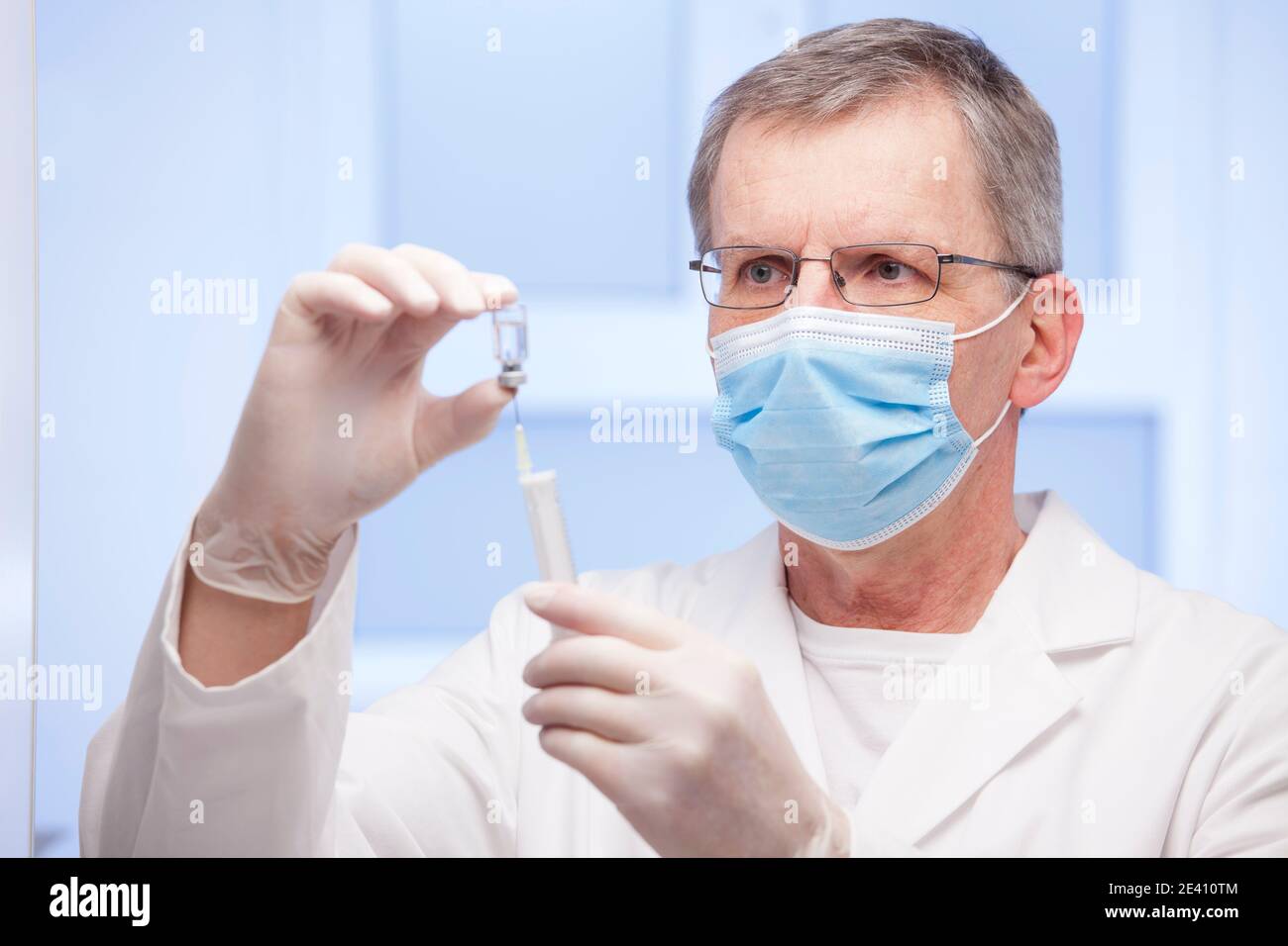 Arzt mit medizinischer Maske Vorbereitung einer Spritze für die Impfung gegen Covid-19 - Fokus auf das Gesicht Stockfoto